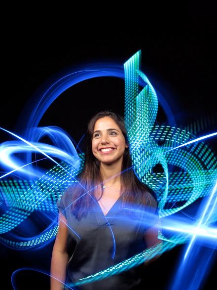 Lächelnde Frau, umgeben von blauen Lichtschleifen und Lichtmustern