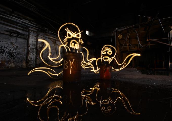 Mit Licht gezeichnete Figuren in einer dunklen Fabrikhalle, im Boden gespiegelt
