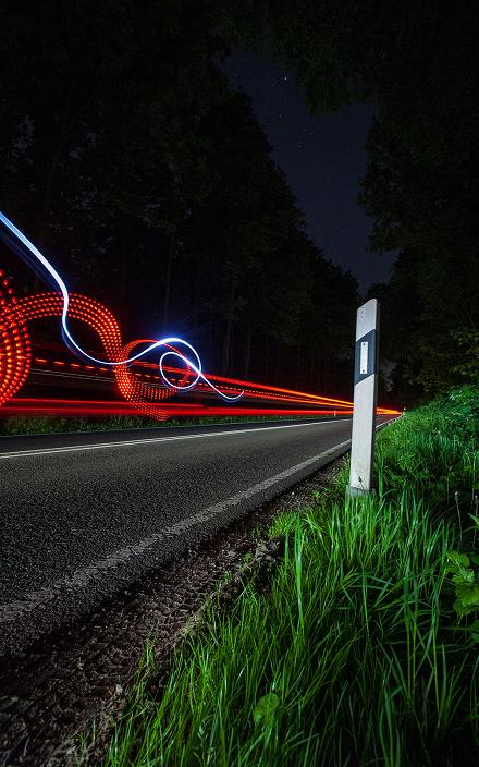 Country road at night with red and blue light trails