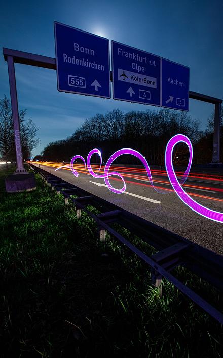 Motorway signs at night with pink light loops at the roadside