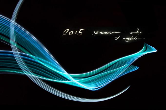 Turquoise ribbons of light and the light writing “2015 year of light” against a black background