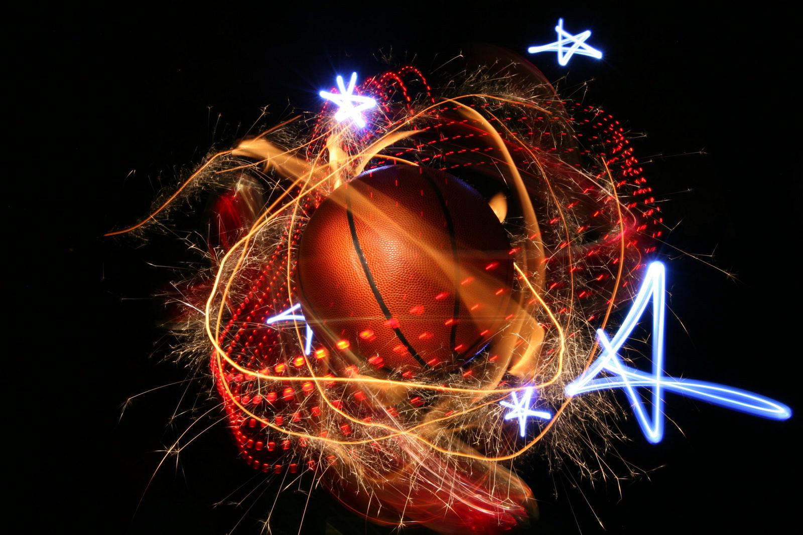 Basketball, umgeben von orange-roten Lichtspuren, Funken und leuchtenden Sternen