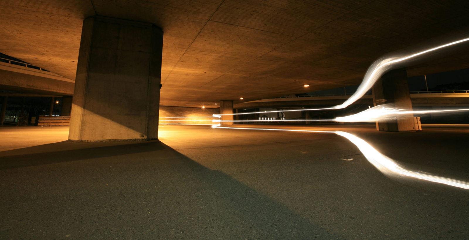 White light trails in an underpass beneath a bridge at night