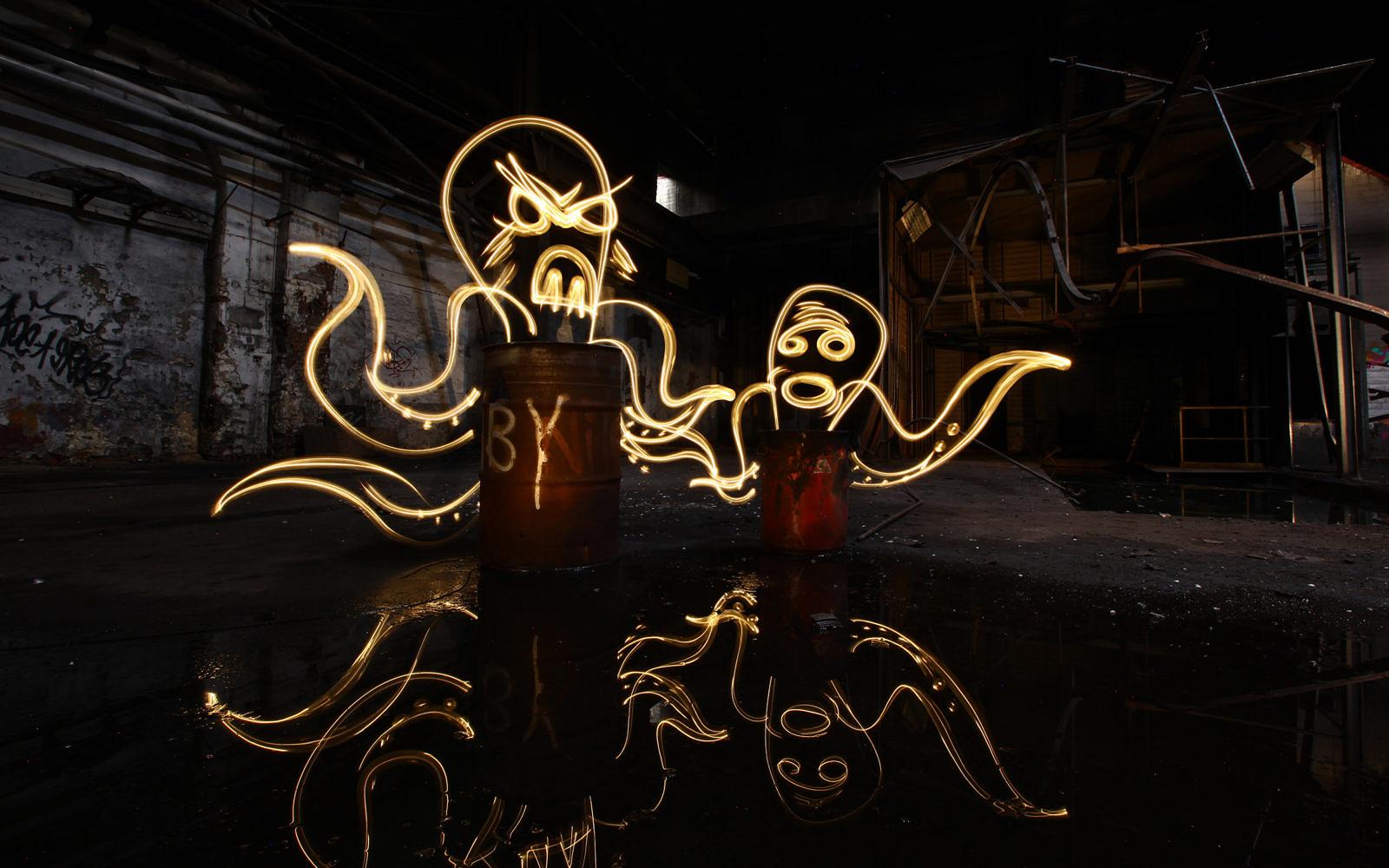 Figures drawn in light in a dark factory hall, reflected in the floor