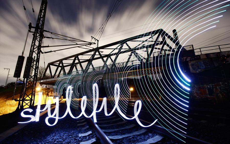 Railway bridge with arcs of light and a word written in light