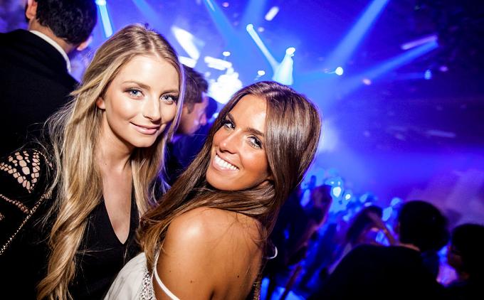 Zwei lachende Frauen in einem Club im blauen Bühnenlicht