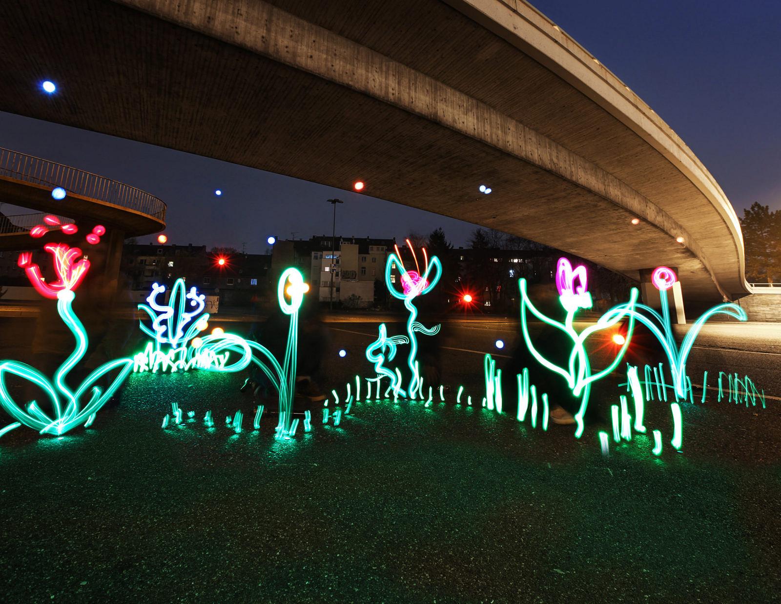 Mit Licht gezeichnete Blumen und Pflanzen unter einer Brücke in der Dämmerung