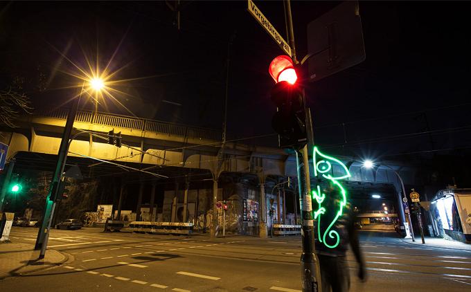 Grüne Lichtzeichnung eines Chamäleons an einer Straßenkreuzung mit Ampel bei Nacht