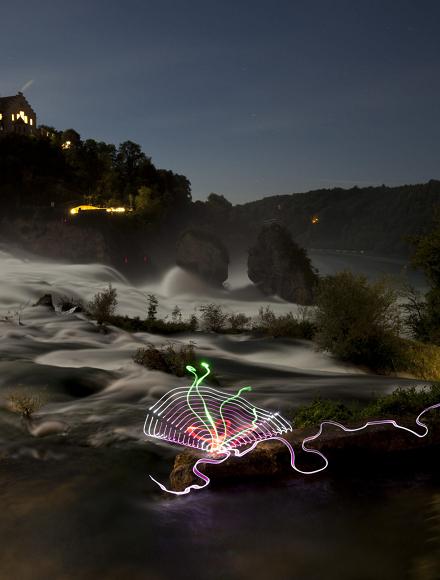 Waterfall at night with a light drawing in the foreground